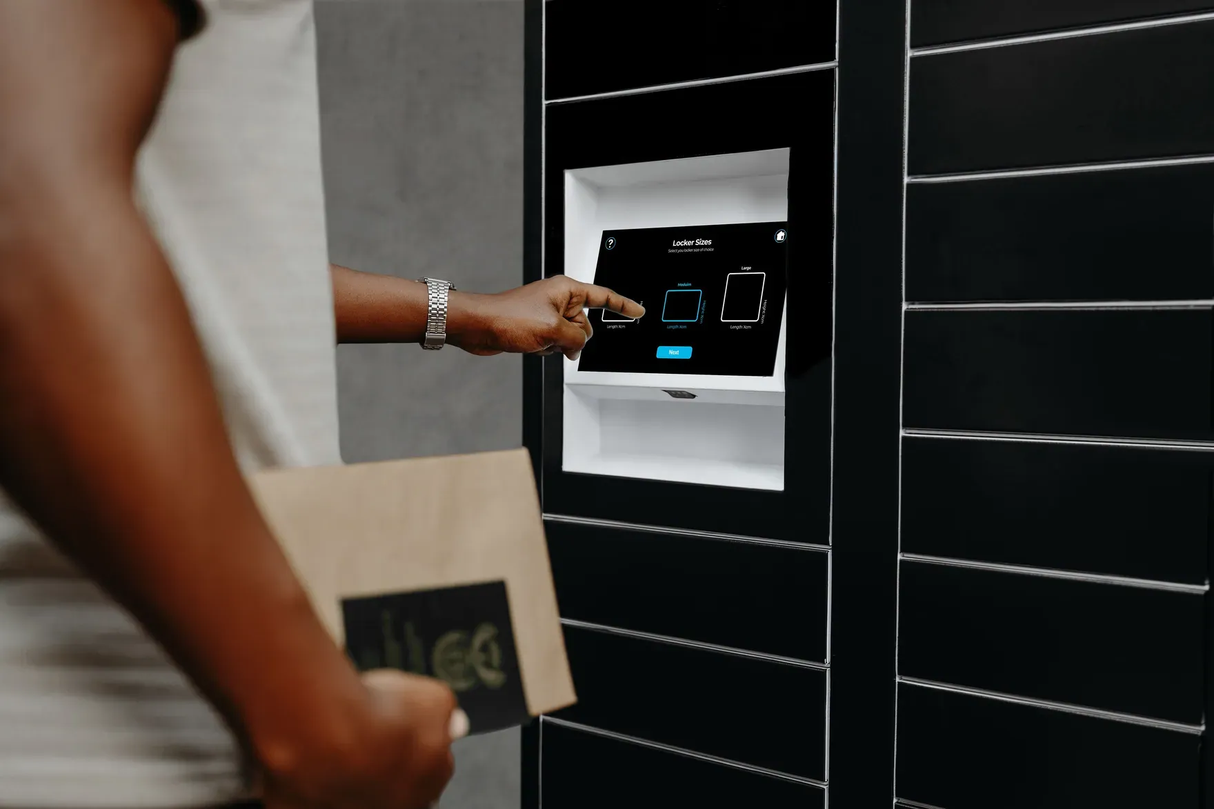 A customer tapping a card on a CollectVault screen while holding a parcel